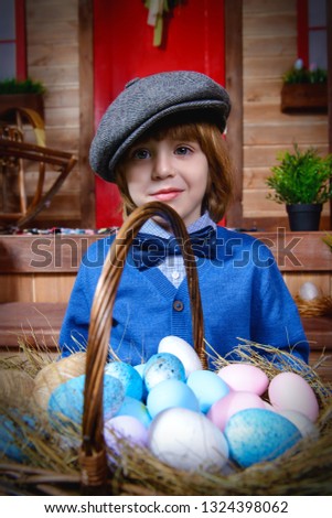Happy little boy is standing on the porch near the wooden house. Easter holiday. Rural style, easter decoration.