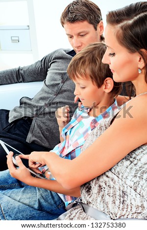 Happy parents with their son looking at touchpad pc together at home.