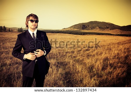 Handsome business man standing in a field with a feeling of freedom.