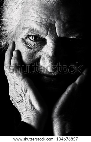 Black-And-White Portrait Of A Calm Senior Woman Looking At The Camera. Over Black Background.