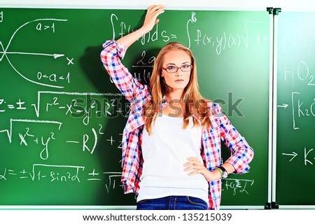 Pretty student girl standing at the blackboard in the classroom.