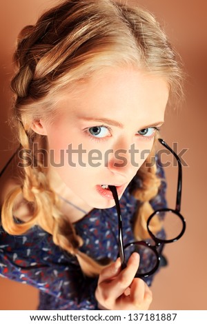 Portrait of a funny blonde girl in big round spectacles looking at camera. Retro style.