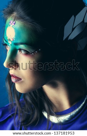 Portrait of a beautiful young woman with fantasy makeup. Dark background.
