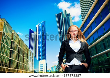 Smiling young business woman standing on the street of the big city.