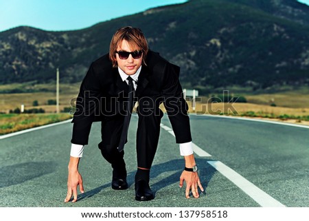Businessman is at the start of running on the highway. Business struggle concept.