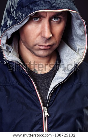 Handsome mature man in hooded jacket looking at camera.