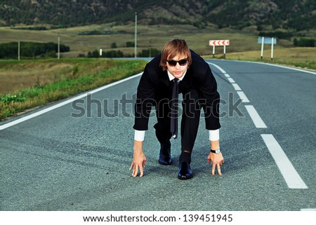 Businessman is at the start of running on the highway. Business struggle concept.
