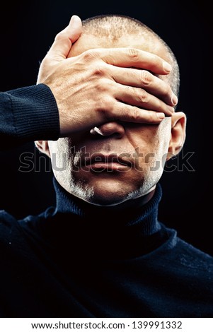 Close-up portrait of a man with closed eyes over black background.