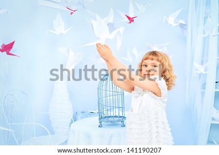 Beautiful little girl in her dream world surrounded with paper birds.