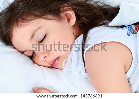 Sweet little girl is sleeping in a bed.