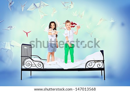 Cute kids standing together on the bed under the blanket. Dream world.