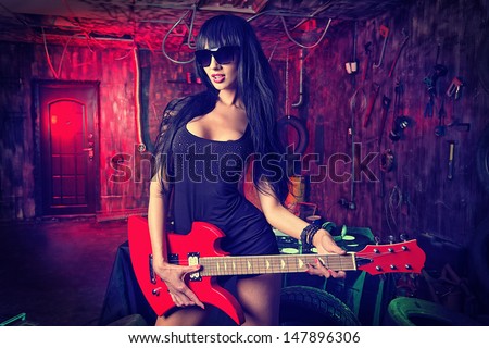 Beautiful sexy girl playing electric guitar in the old garage.