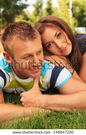 Beautiful happy couple having a rest in the park in sunny summer day.
