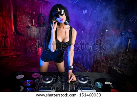 Beautiful sexy DJ girl working on a party in the old garage.
