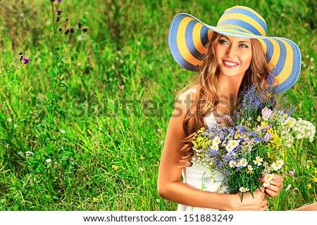 Portrait of a romantic smiling young woman with a bouquet of wild flowers outdoors.