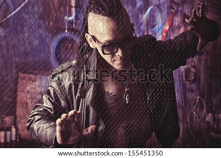 Modern young man with dreadlocks in the old dark garage.