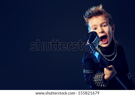 Emotional little boy is singing into a microphone like a rock musician.