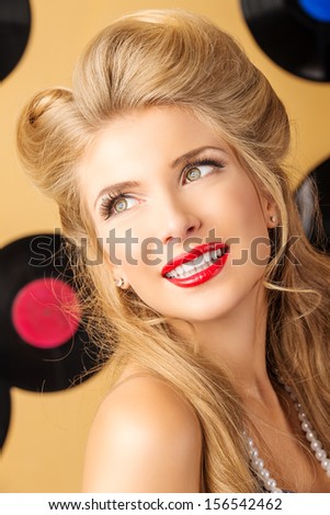Portrait of a charming pin-up woman with retro hairstyle and make-up posing with vinyl record.