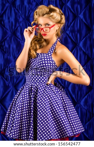 Charming pin-up woman with retro hairstyle and make-up wearing spectacles.
