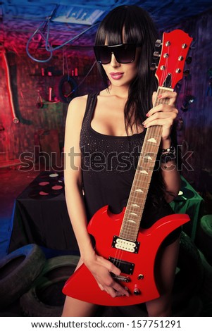 Beautiful sexual girl playing electric guitar in the old garage.