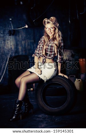 Charming pin-up woman with retro hairstyle and make-up in the old garage.