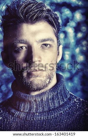 Portrait of a handsome man dressed in winter clothes, covered with frost and snow.