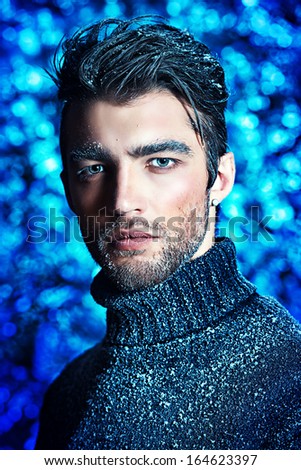 Portrait of a handsome man dressed in winter clothes, covered with frost and snow.