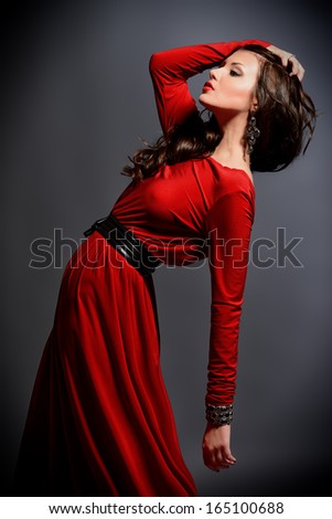 Fashion shot of a gorgeous young woman in elegant red dress.