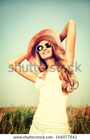 Beautiful Young Woman In Elegant Hat And Sunglasses Posing Over Sky.