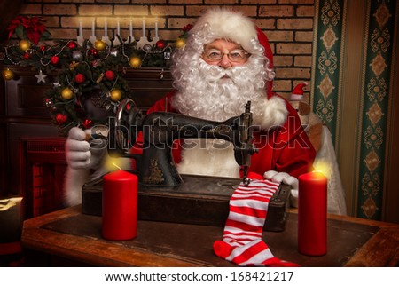 Santa Claus is sewing on a sewing machine striped socks for Christmas.
