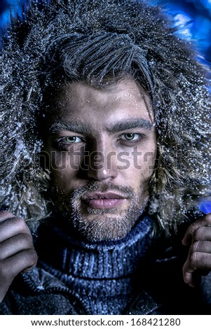 Portrait of a handsome man dressed in winter clothes, covered with snow.