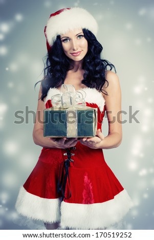 Portrait of a charming smiling young woman in Christmas costume with a gift.
