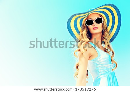 Stunning young woman in elegant hat and sunglasses posing over sky.