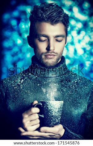 Portrait of a handsome man dressed in winter clothes, covered with frost, drinking hot tea.
