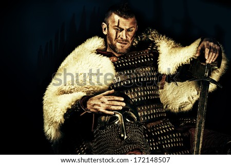 Portrait Of A Courageous Ancient Warrior In Armor With Sword And Shield.