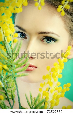 Portrait of a beautiful girl with mimosa flowers. Spring.