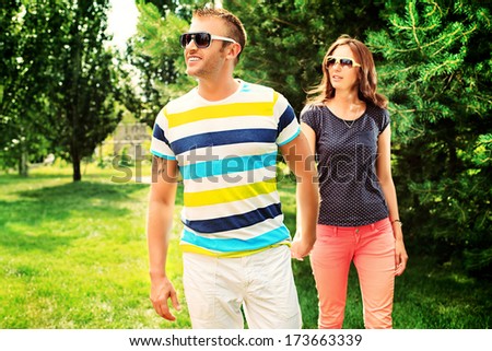 Beautiful happy couple walking in the park in sunny summer day.