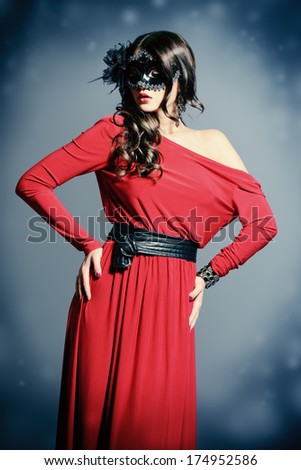 Fashion shot of a charming  woman in beautiful red dress and ornate carnival mask.