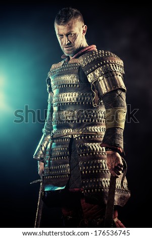 Portrait of a courageous ancient warrior in armour with sword.