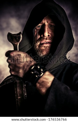 Portrait of a courageous warrior wanderer in a black cloak and sword in hand. Historical fantasy.