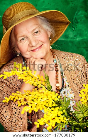 Portrait of a beautiful elderly woman with mimosa flowers. Happy old age.