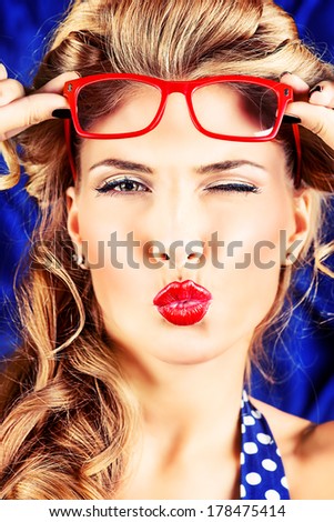 Charming pin-up woman with retro hairstyle and make-up sending a kiss.