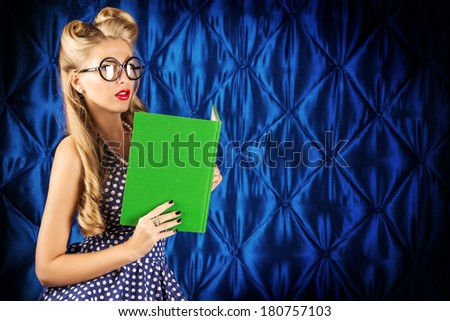 Beautiful pin-up woman with retro hairstyle and make-up posing with a book.