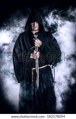 Portrait of a courageous warrior wanderer in a black cloak and sword in hand. Historical fantasy.