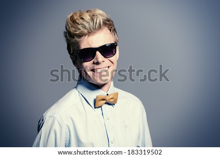 Portrait of a modern handsome young man in sunglasses smiling at camera. Studio shot.