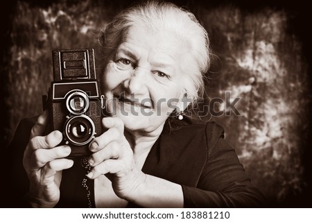 Portrait of a beautiful old lady with her old camera. Vintage, retro style.