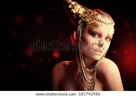 Art project: beautiful woman with golden make-up. Jewelry, make-up. Fashion. Over black background.