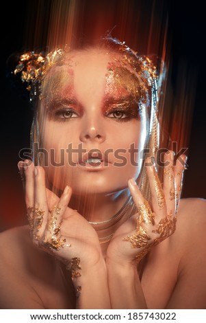 Art project: beautiful woman with golden make-up over black background. Jewelry, make-up. Fashion. Light effects.