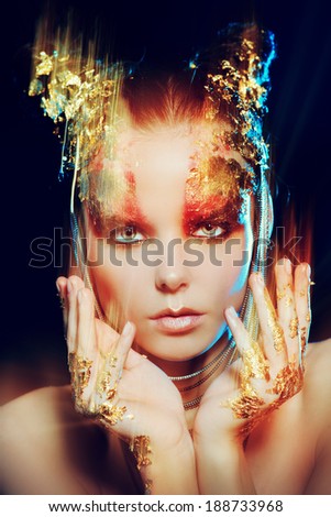 Art project: beautiful woman with golden make-up over black background. Jewelry, make-up. Fashion. Light effects.