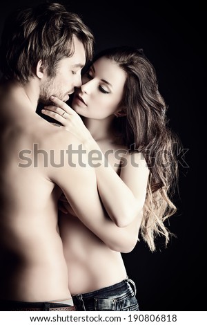 Beautiful passionate naked couple in love. Over black background.
